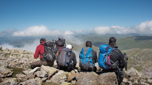 A group of five walkers rest above the clouds at the summit of Great End, Wasdale, Cumbria